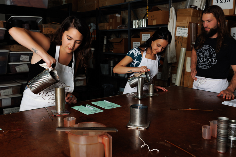 Candle class instructor, Ryder, watches over two participants while making column candles in Waxman's studio space.