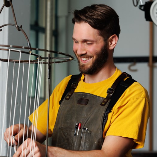 Waxman's head candle maker, Mitch, stands wicking a taper rack in Waxman's candle studio.